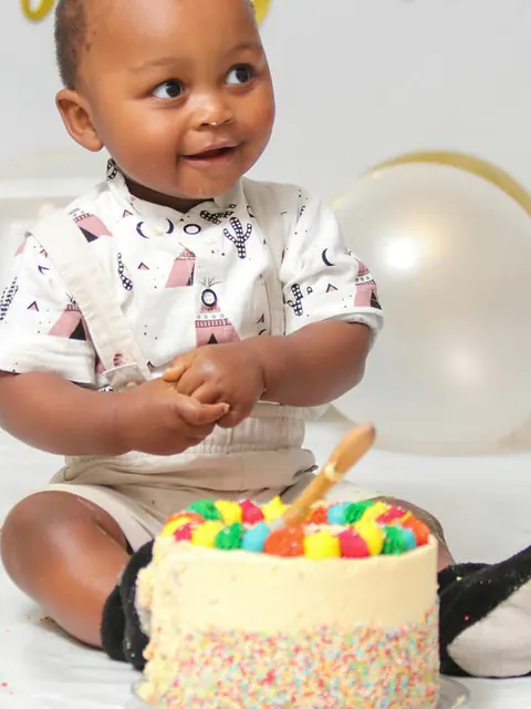 Um bebê sorrindo diante do bolo de aniversário