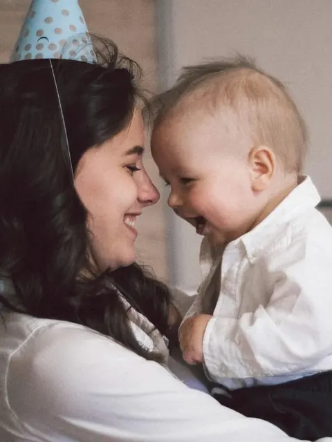 Uma mãe e seu bebê de testas encostadas, rindo