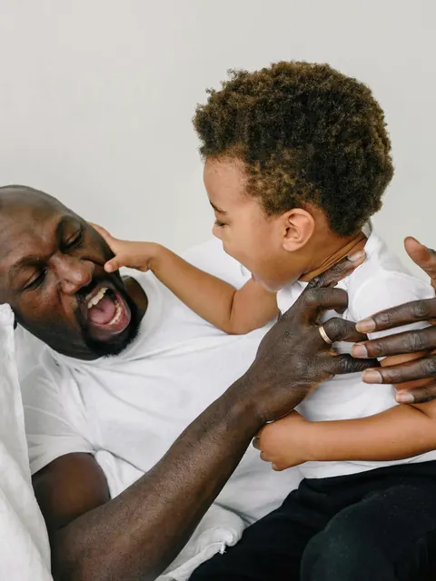 Um pai e o filho pequeno rindo juntos na cama